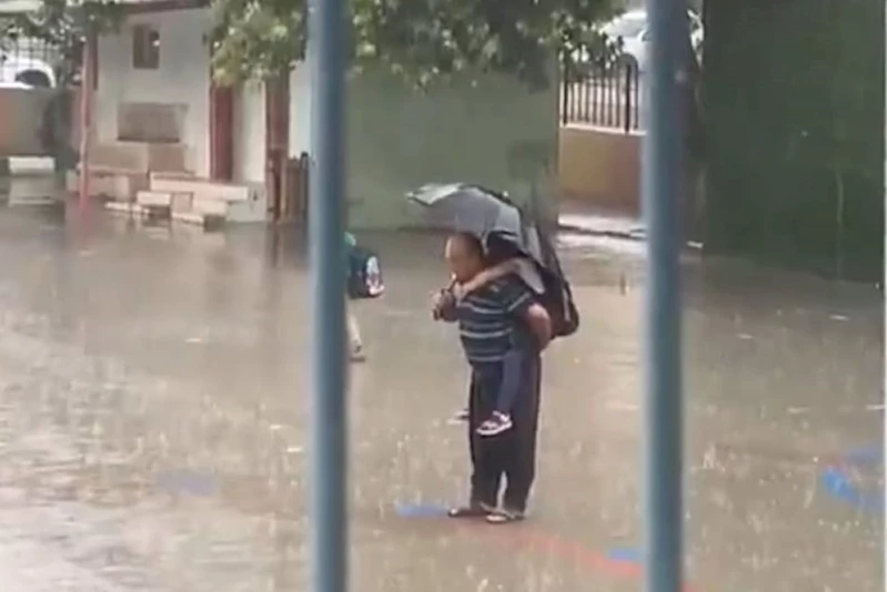 Dede torununu sırtına alarak yağmur altında İstiklal Marşı okudu
